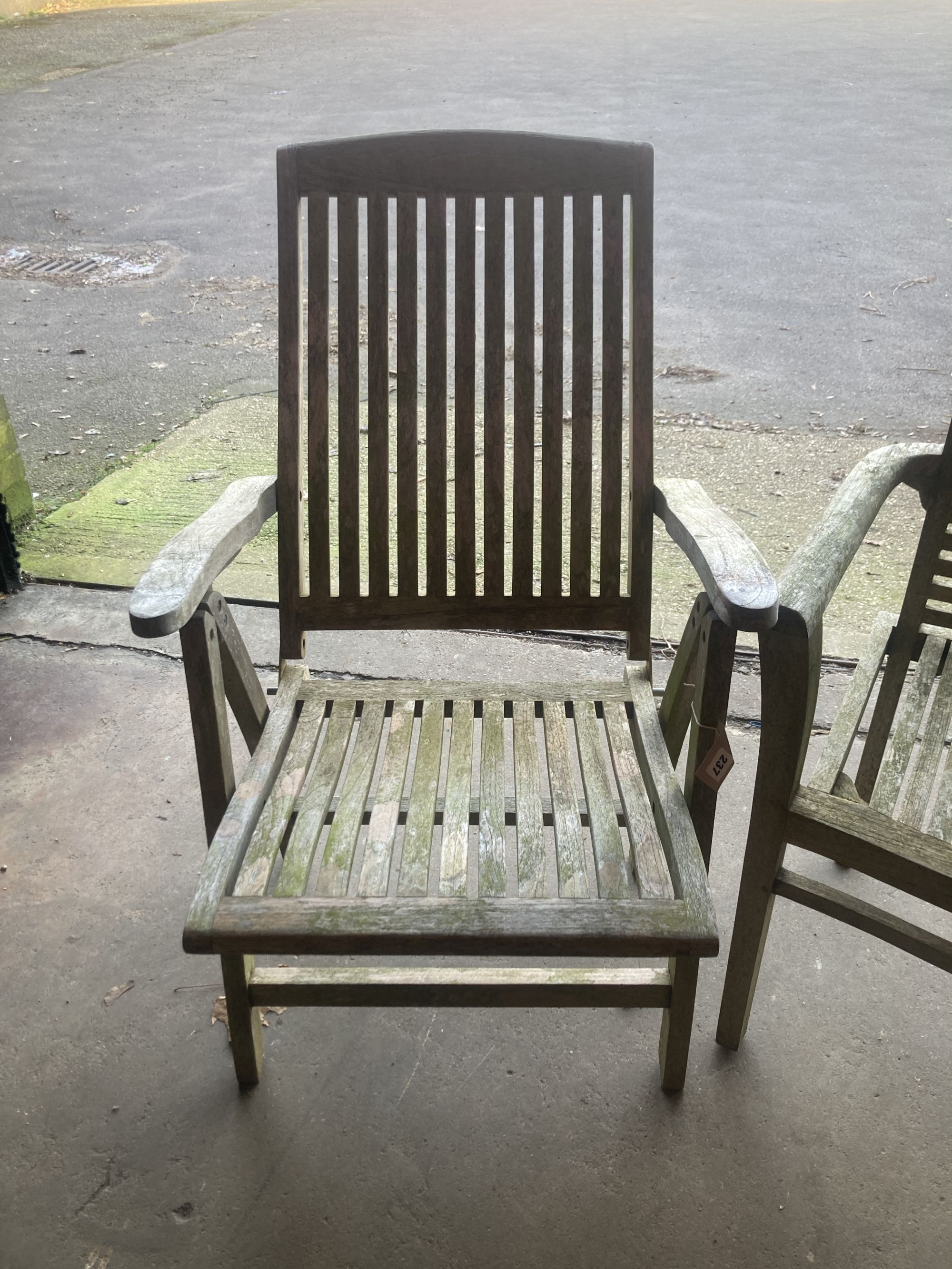 A weathered teak folding garden armchair, together with a teak garden elbow chair